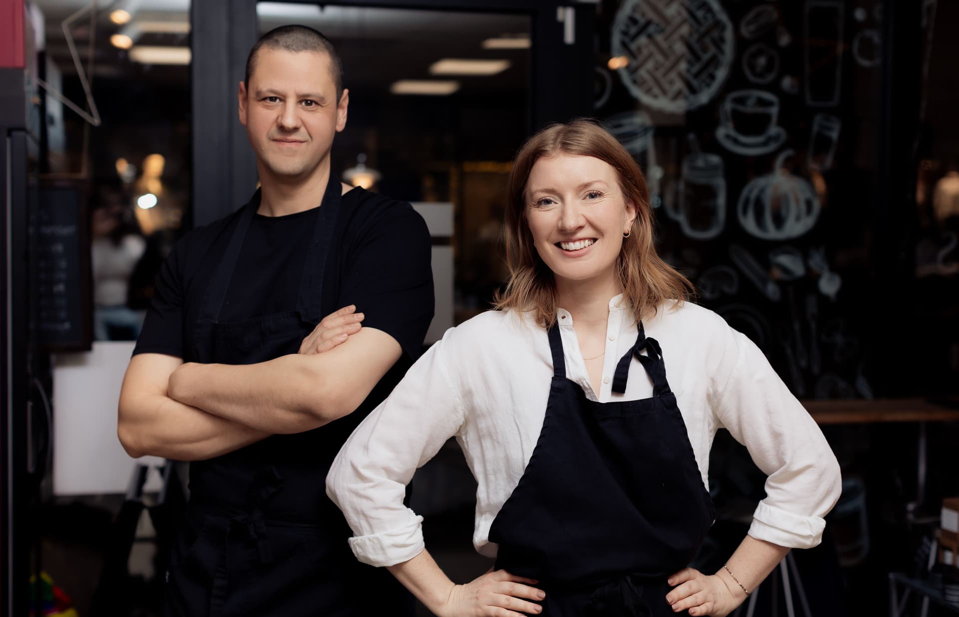 Man and woman in aprons smiling at camera
